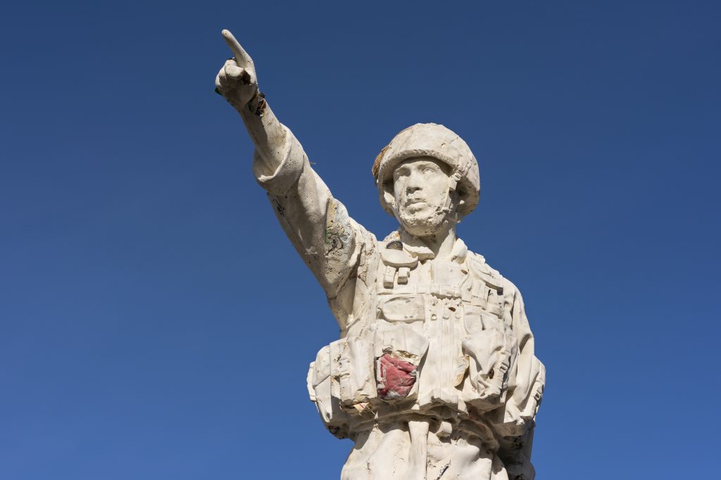 A sculpture of a young soldier from the Iraq war pointing out to sea